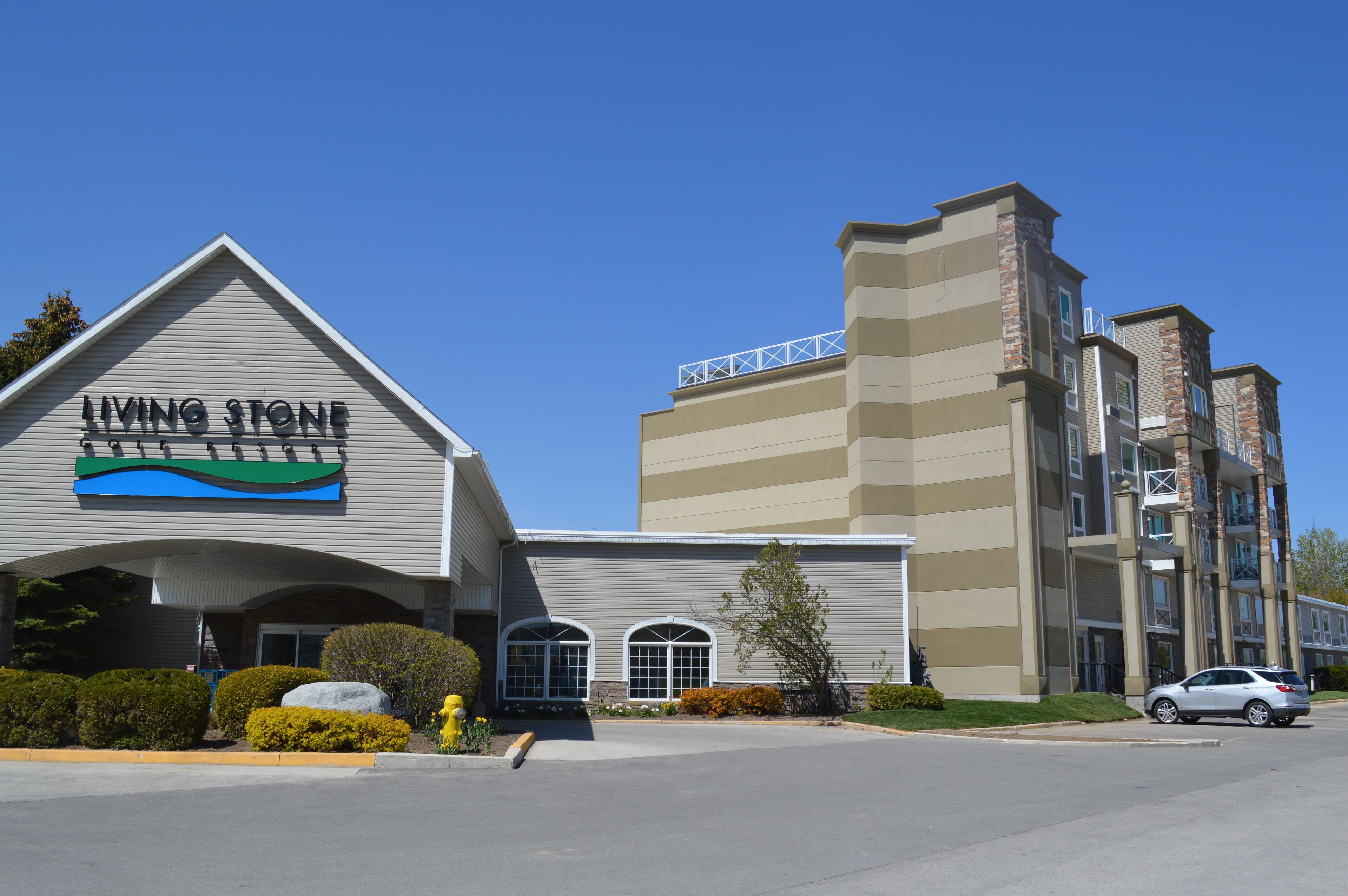 A building with a 'Living Stone' sign, a parking lot, and a clear blue sky.