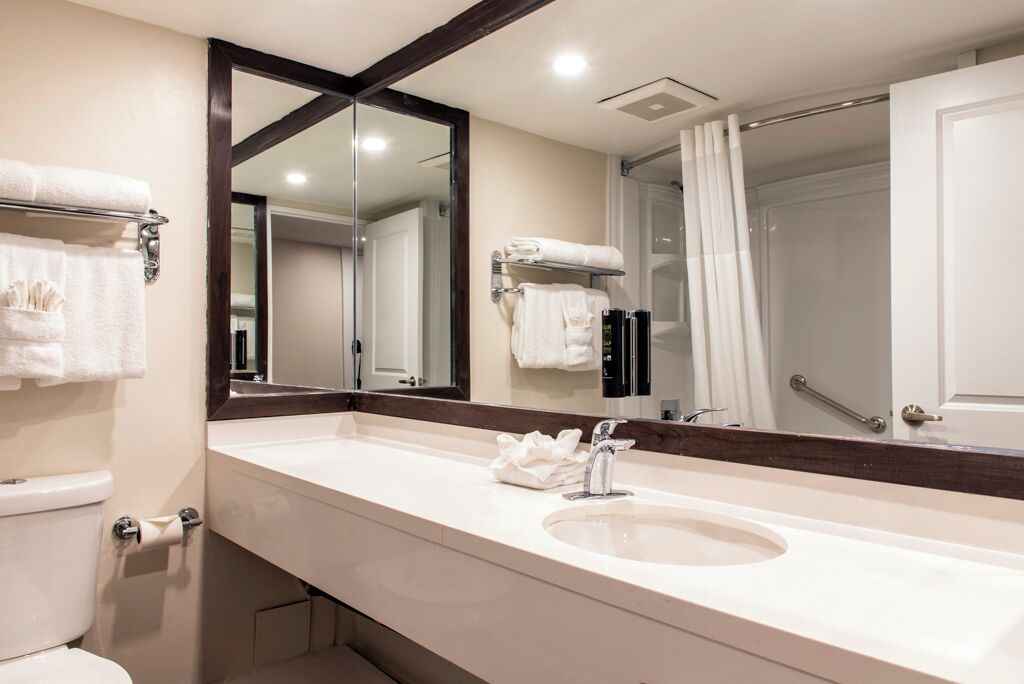 A modern bathroom with a large mirror, a sink, and a toilet.