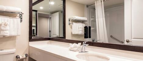 A modern bathroom with a large mirror, a sink, and a toilet.