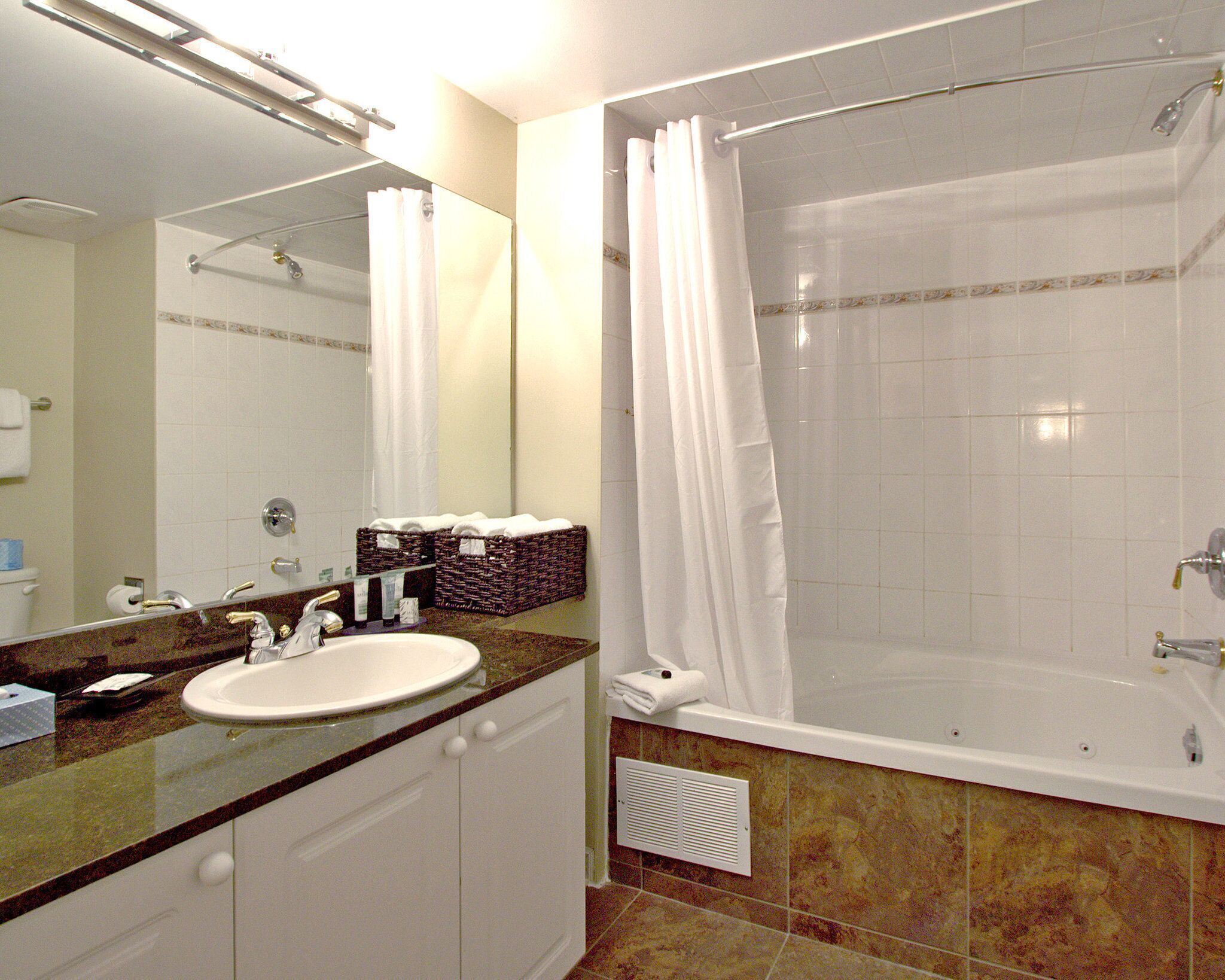 A bathroom with a sink, mirror, and a bathtub with a shower curtain.