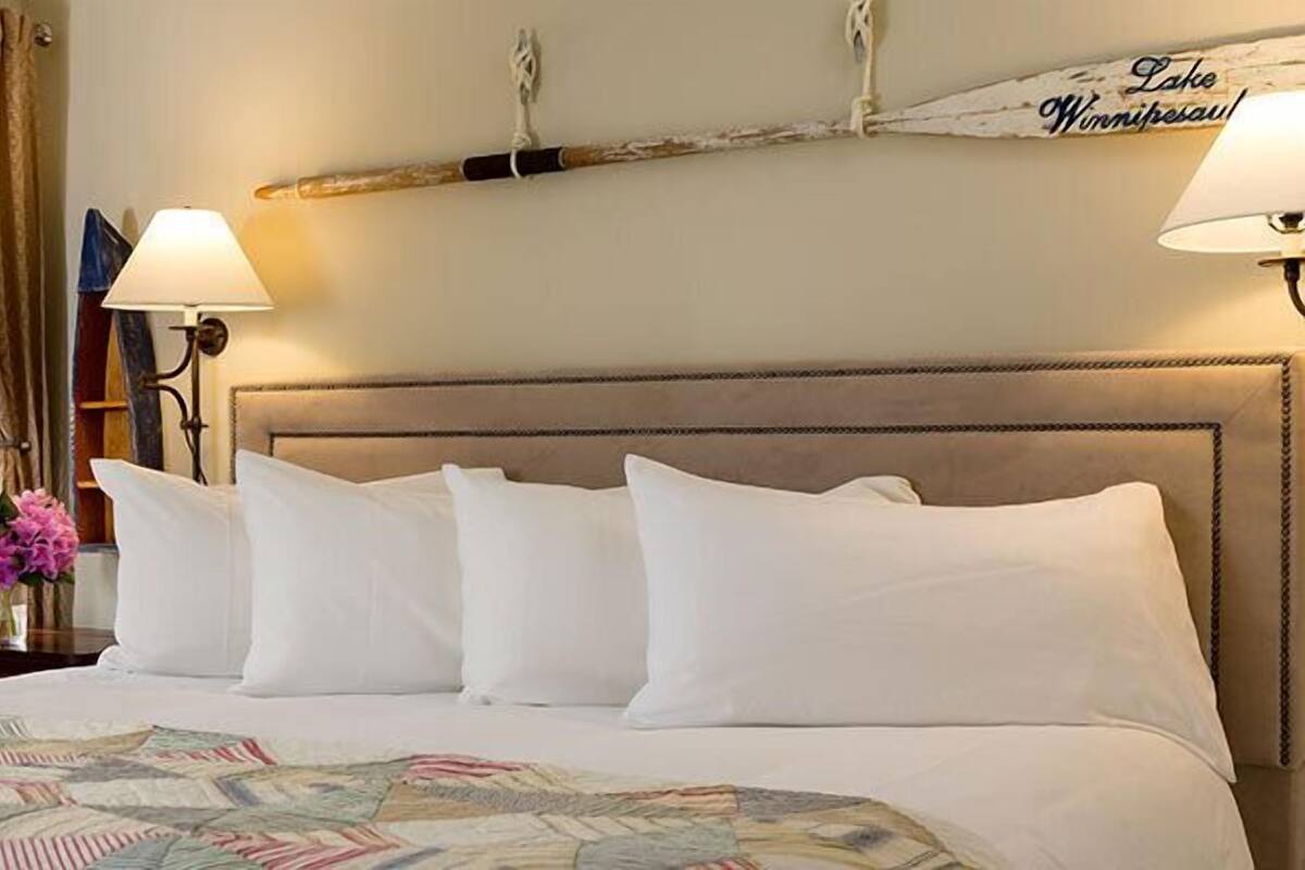 Une chambre d’hôtel avec un grand lit, une table de chevet, une lampe et une vue sur l’extérieur.