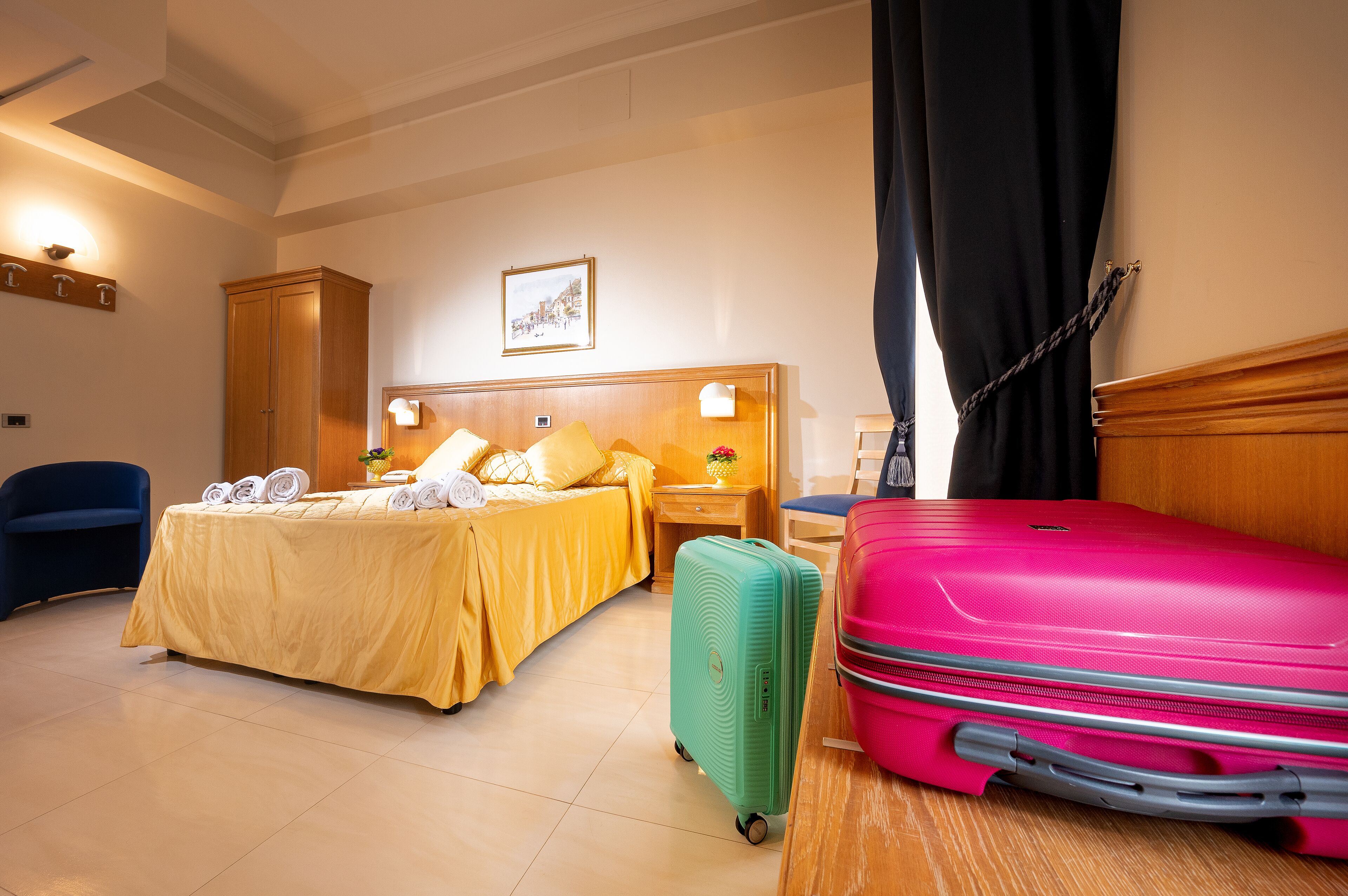 Een hotelkamer met een bed, een nachtkastje, een lamp en twee koffers.