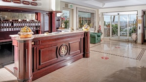 A hotel lobby with a reception desk, a large window, and a view of the city. - Sabbie d'Oro (Giardini Naxos)
