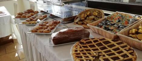 Una mesa de buffet con diversas opciones de productos horneados, como pasteles, tartas y pan.