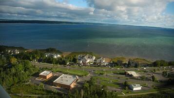 An aerial view of a coastal town with residential buildings, a parking lot, and a road leading to the beach.