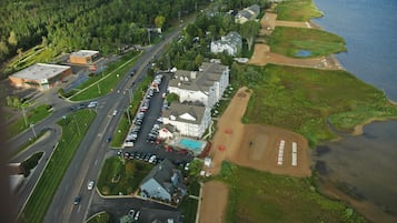 Luftaufnahme einer Küstenregion mit einem großen Gebäudekomplex, Parkplätzen und einem Strand.