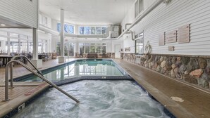 An indoor swimming pool with a stone wall and a lifeguard sign.
