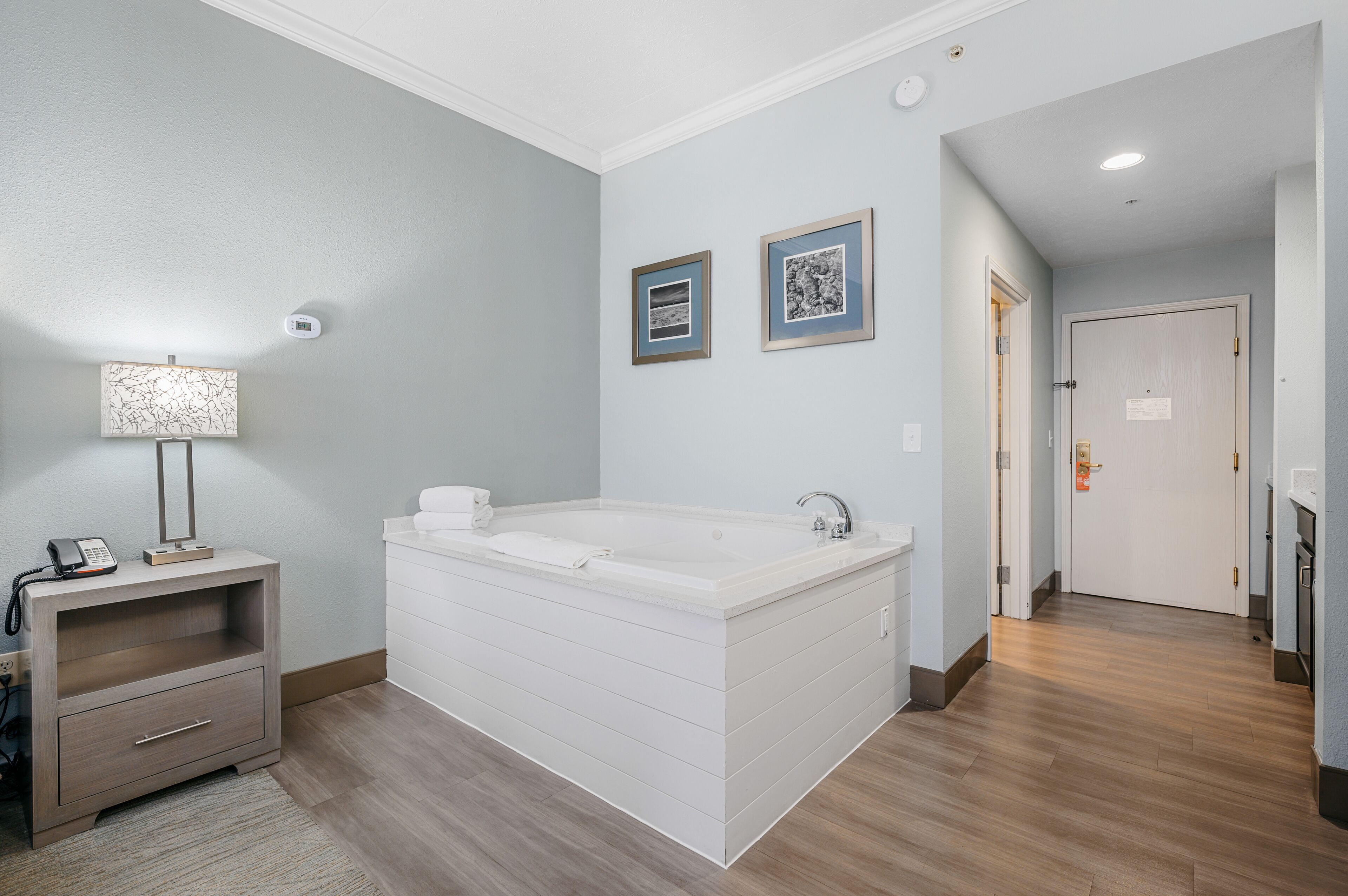 A modern bathroom with a freestanding bathtub, a vanity with a mirror, and two framed pictures on the wall.