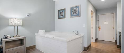 A modern bathroom with a freestanding bathtub, a vanity with a mirror, and two framed pictures on the wall.