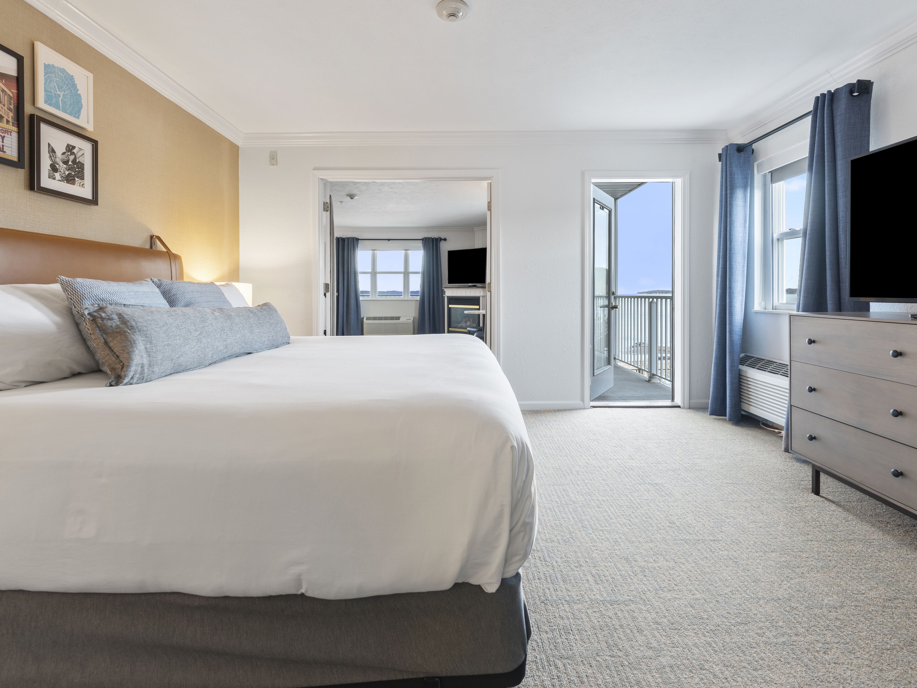 Une chambre d’hôtel avec un grand lit, une commode, un téléviseur à écran plat et un balcon avec vue.