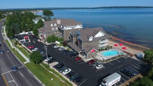 An aerial view of a hotel with a swimming pool, parking lot, and a view of a lake.