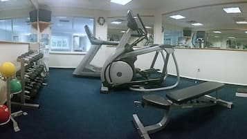 A gym with treadmills, a bench, and various weights.
