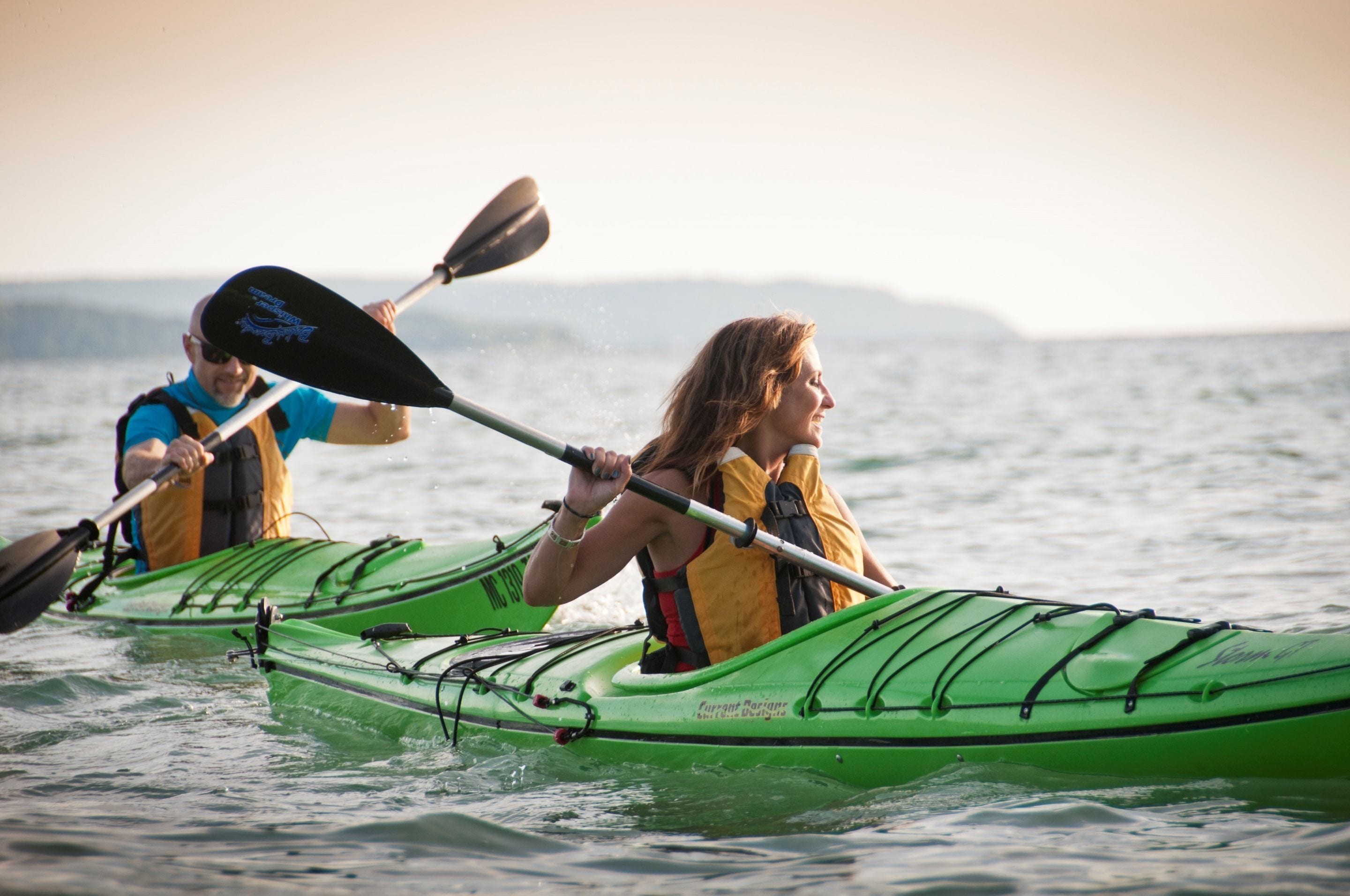 Deux personnes pratiquent le kayak sur une étendue d’eau calme.