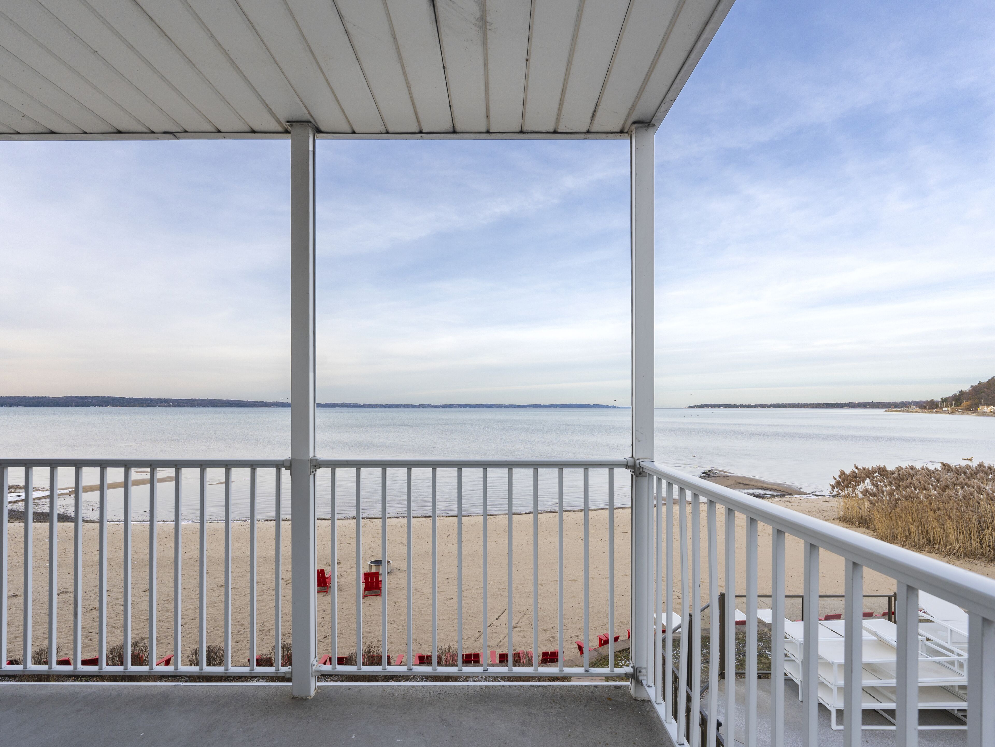 Un balcon abrité offrant une vue sur une plage de sable et une eau calme.