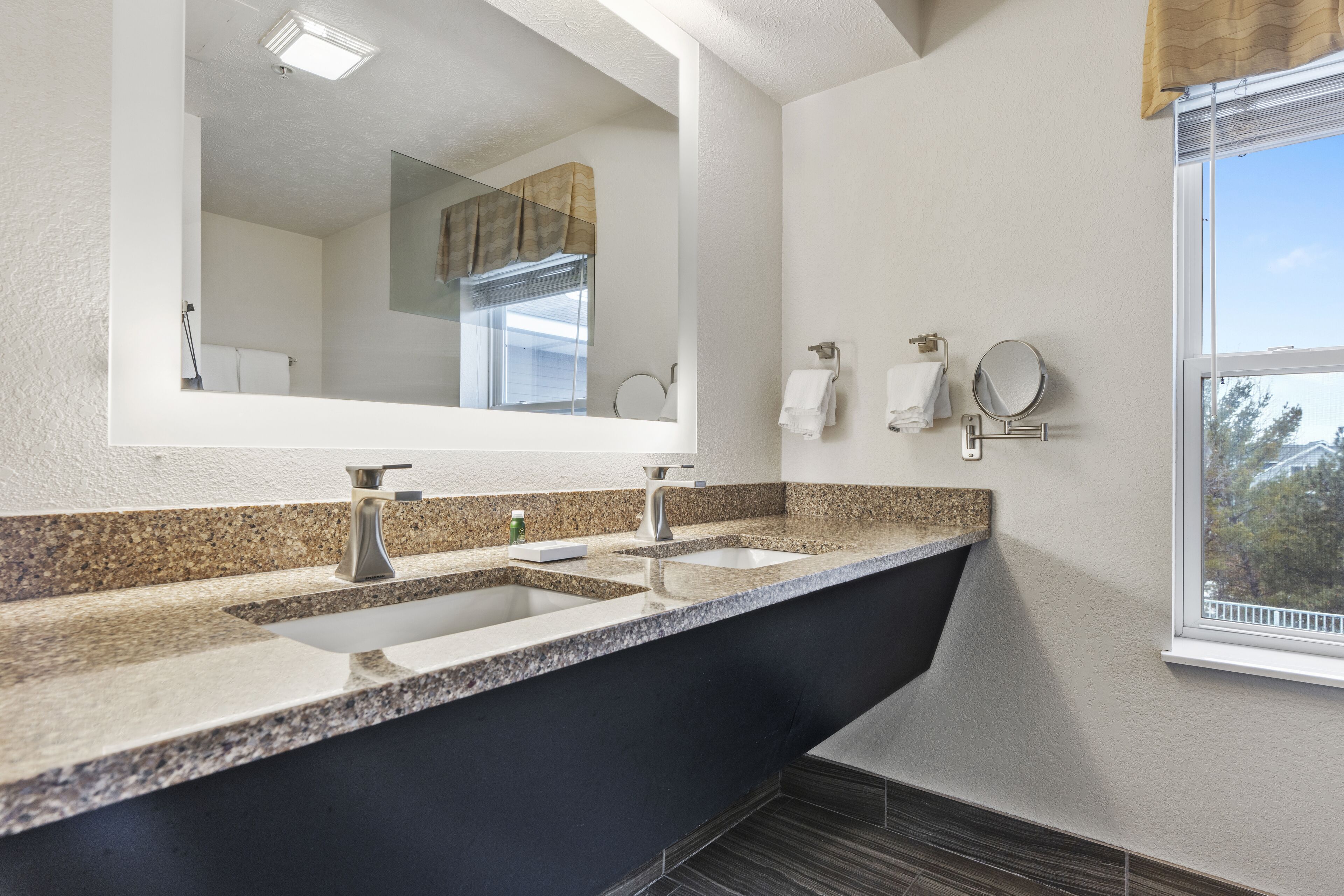 Een moderne badkamer met een ruim badkamermeubel, twee wasbakken, een spiegel en een raam.