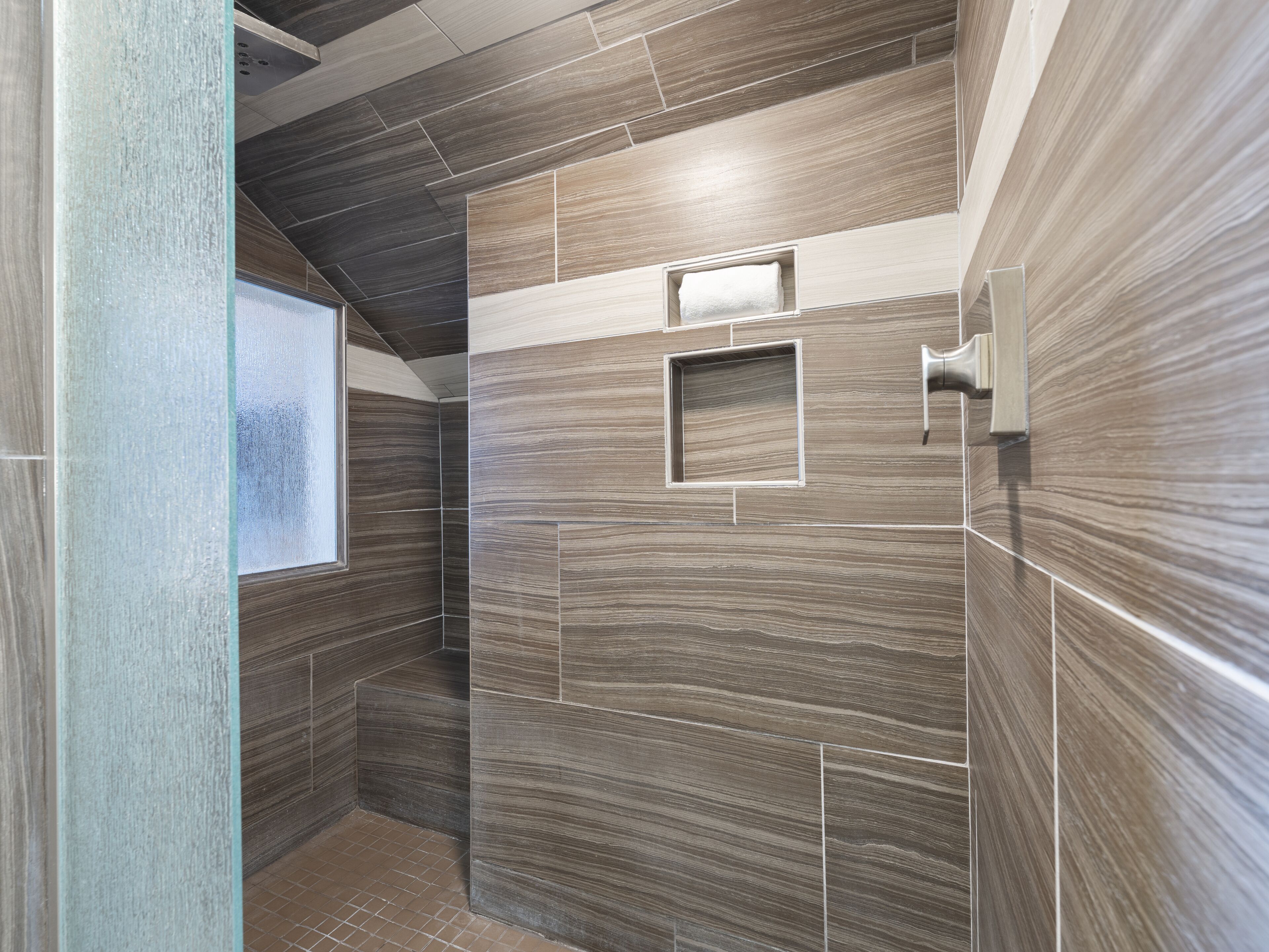 A modern bathroom with a shower area, tiled walls, and a window.