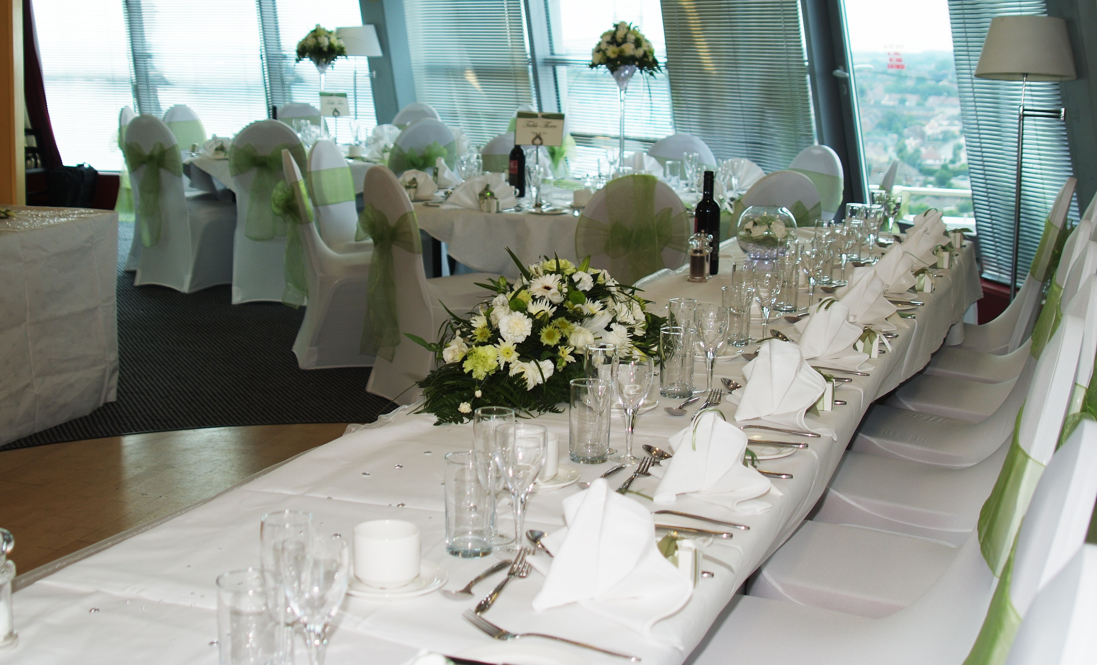 Ein festlich gedeckter Bankettisch mit weißen Tischdecken, Gläsern und floralen Mittelpunkten.