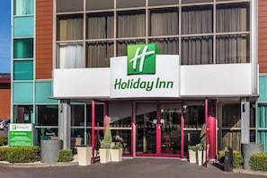 A Holiday Inn hotel entrance with a clear sign, automatic doors, and a guest parking sign. - Holiday Inn Birmingham North - Cannock by IHG (Cannock)
