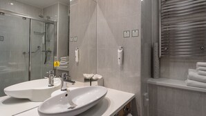 Une salle de bain moderne avec deux lavabos, une douche à parois de verre et un porte-serviettes.