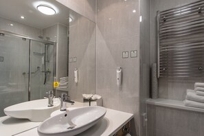 A modern bathroom with two sinks, a glass shower enclosure, and a towel rack. - Holiday Inn Birmingham North - Cannock by IHG (Cannock)