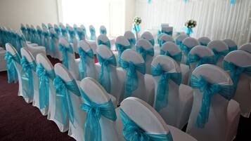 Rows of chairs with white covers and blue sashes.