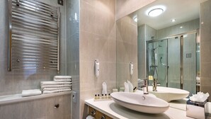 Une salle de bain moderne avec un grand miroir, deux lavabos, une douche et un porte-serviettes.
