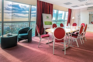 A conference room with a city view, red chairs, a round table, and a 'Holiday Inn' sign. - Holiday Inn Birmingham North - Cannock by IHG (Cannock)