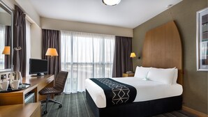 Une chambre d’hôtel avec un grand lit, un bureau avec un ordinateur, une chaise et une télévision.