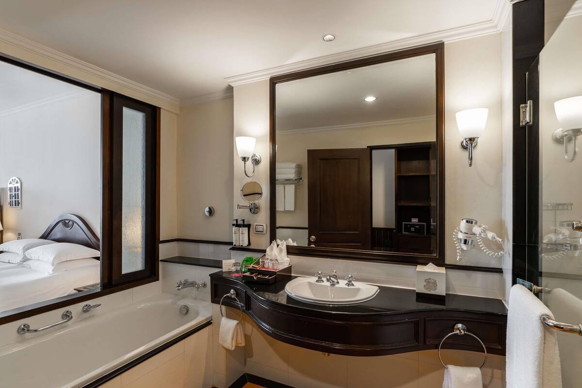 Ein modernes Hotelbad mit einem großen Spiegel, einer Badewanne, einem Waschbecken und einer Duschkabine.