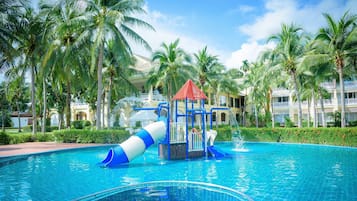 Relax by the pool surrounded by lush palm trees and enjoy a fun water slide and play structure.