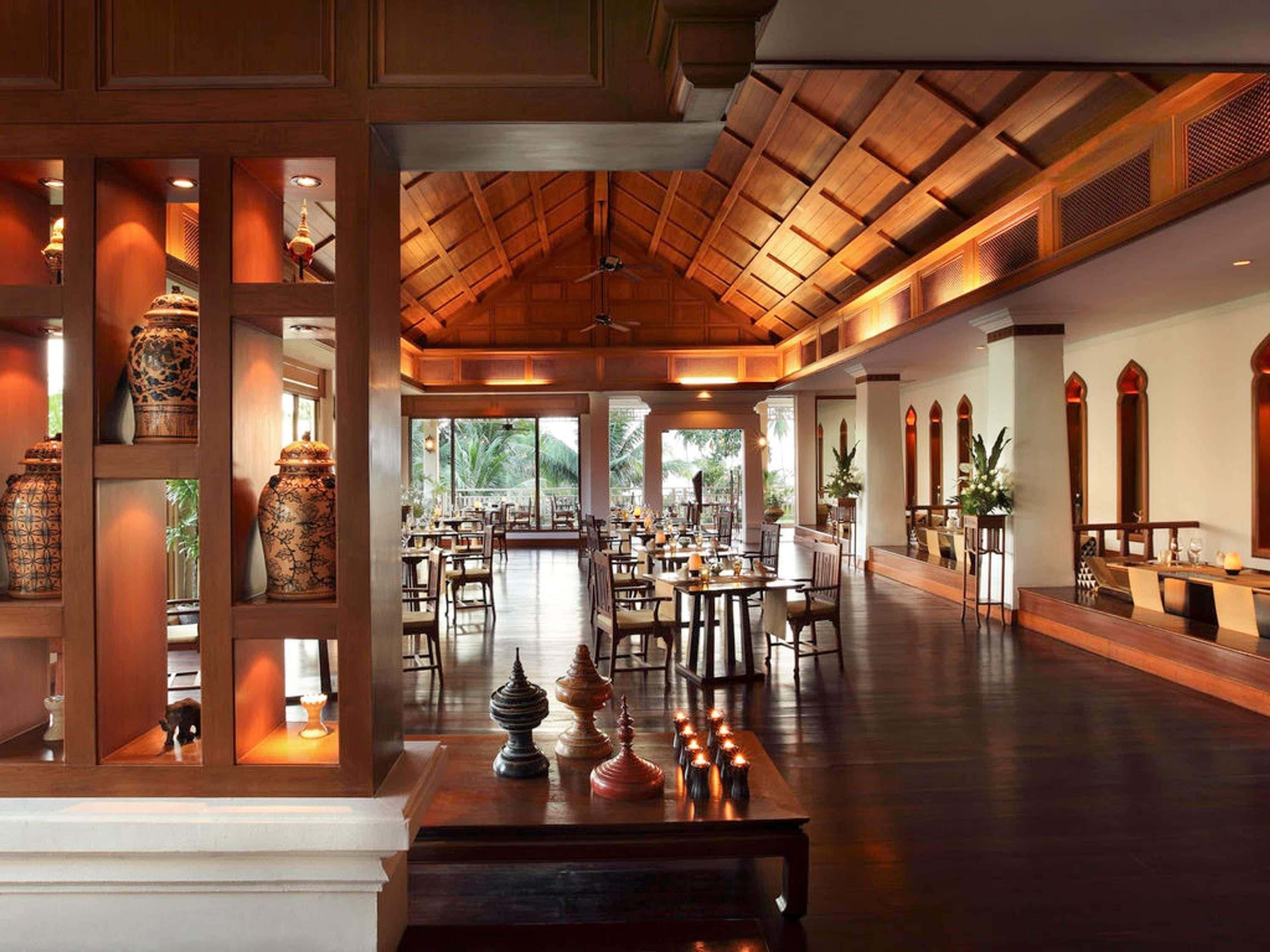 A spacious hotel lobby with wooden paneling, large windows, and a ceiling fan.