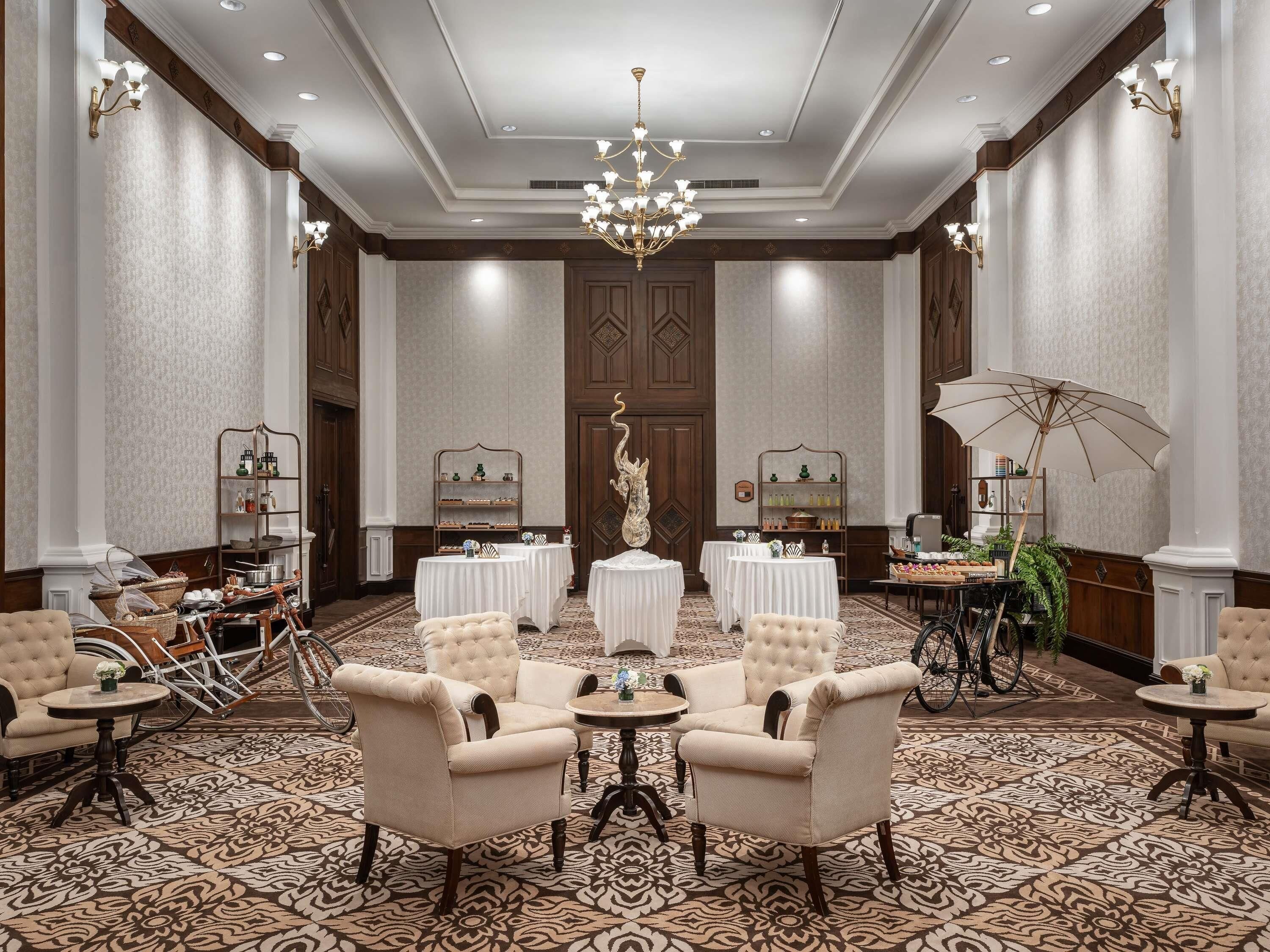A spacious lobby with a high ceiling, chandeliers, and a patterned carpet.