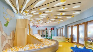 Un espace de jeux pour enfants avec une piscine à balles, des structures d’escalade et des jouets éducatifs.