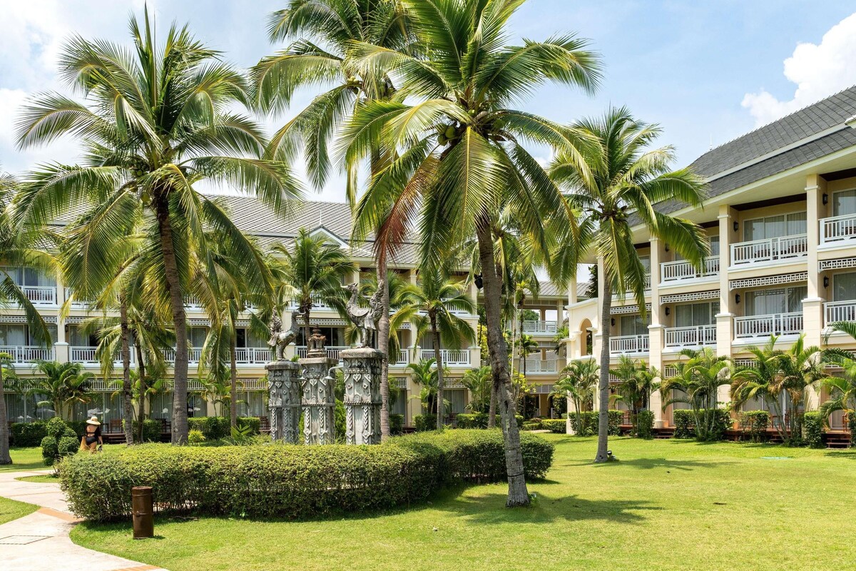 Un hôtel à étages, bordé de palmiers et doté d’une pelouse bien entretenue.