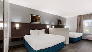 A hotel room with two beds, a large window with curtains, and wall-mounted lights. - MainStay Suites Extended Stay Hotel Casa Grande (Casa Grande)