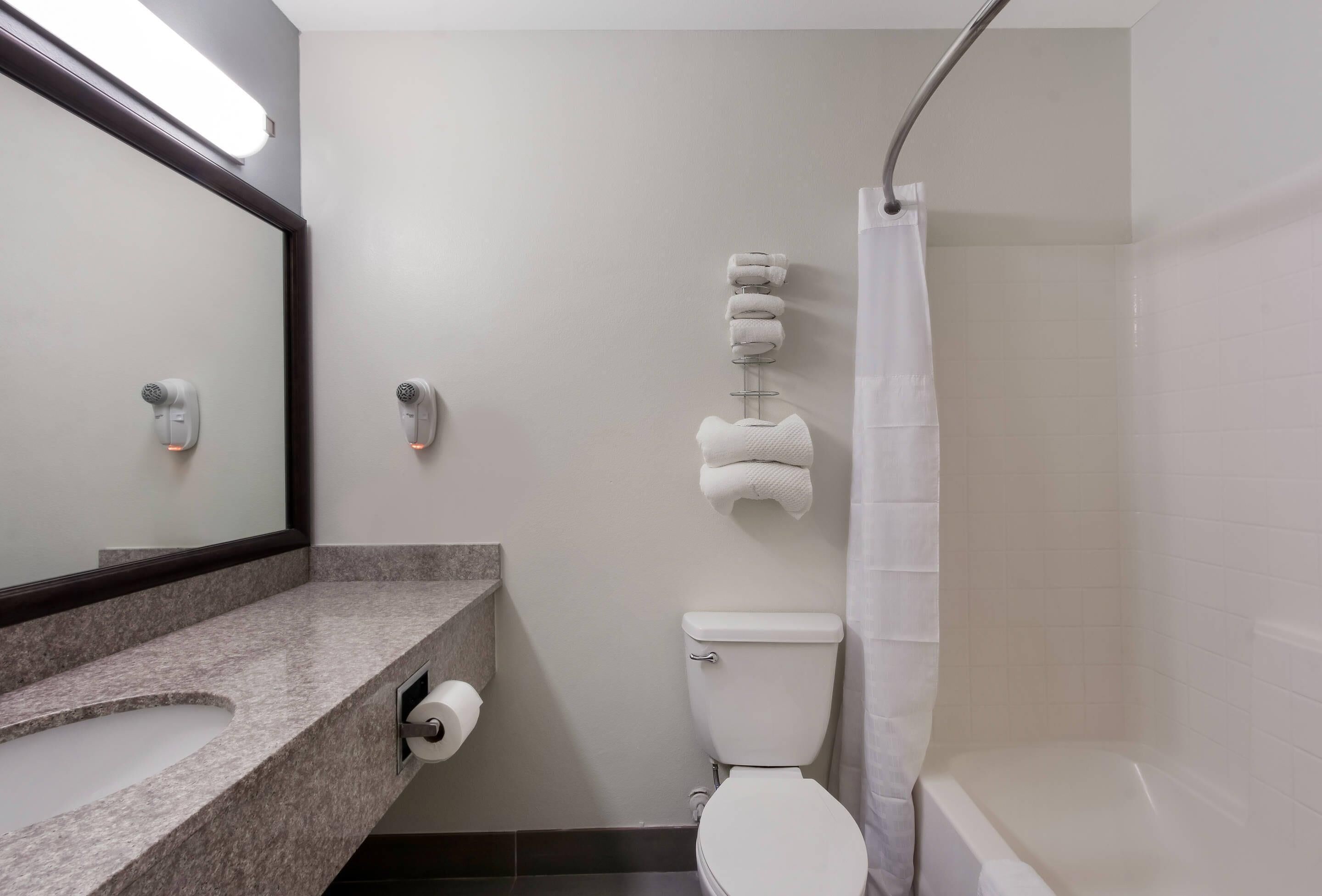 Un baño con inodoro, lavamanos, toallero y cortina de ducha.