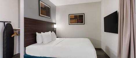 A hotel room with a bed, a wardrobe, a flat-screen TV, and a wall-mounted picture.