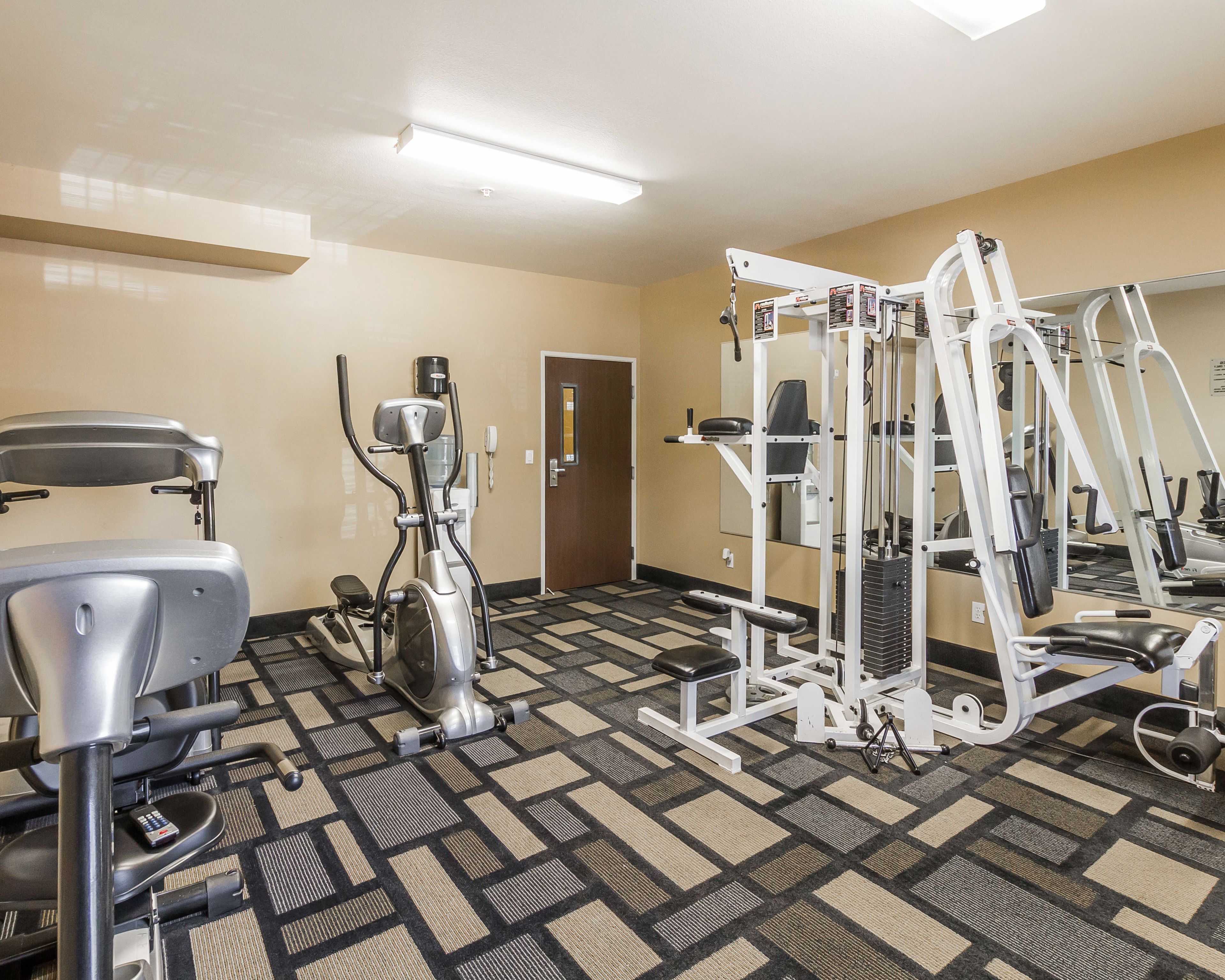 A gym with exercise equipment, a door, and a patterned carpet.