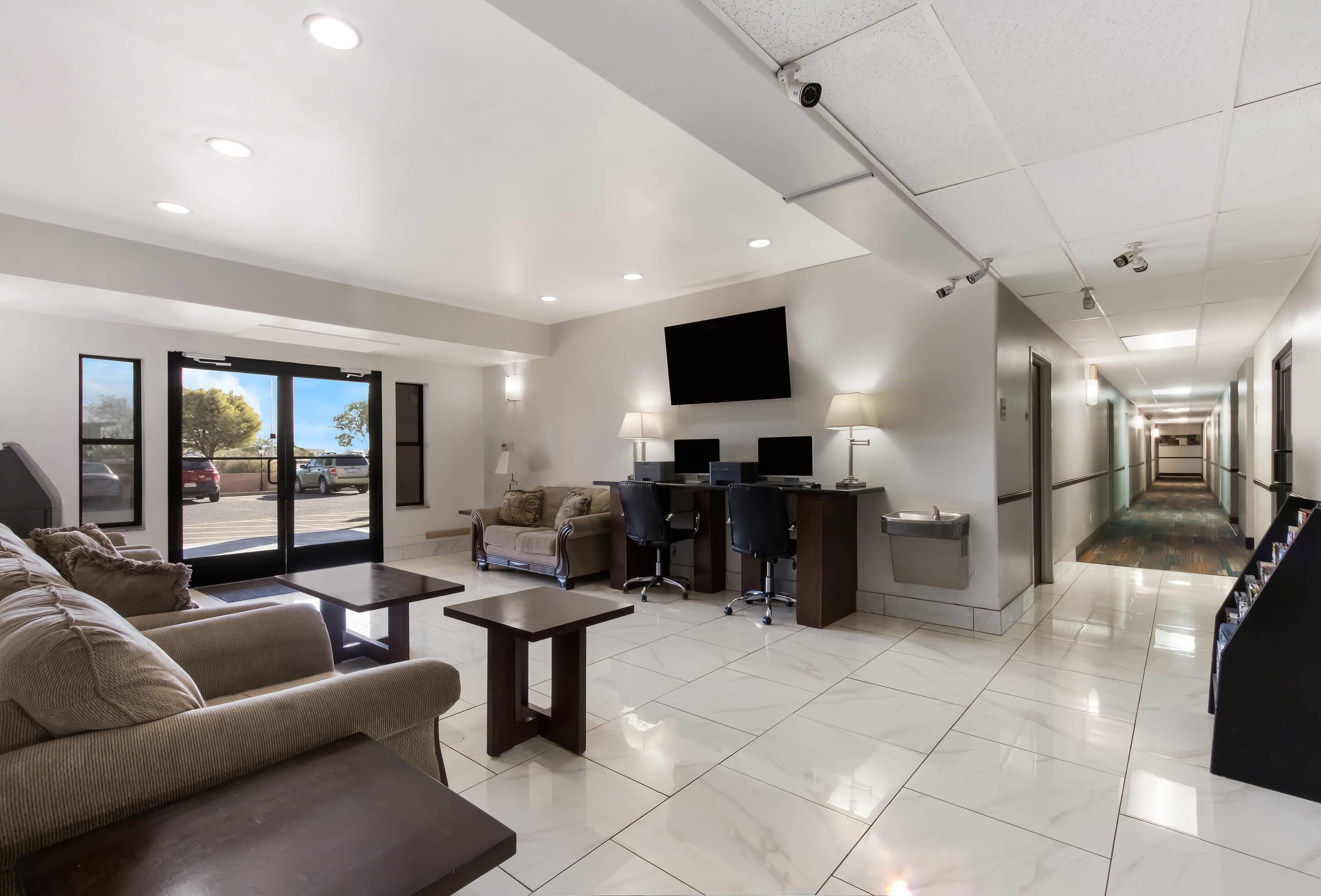A spacious lobby with a seating area, a reception desk, and a large TV screen.