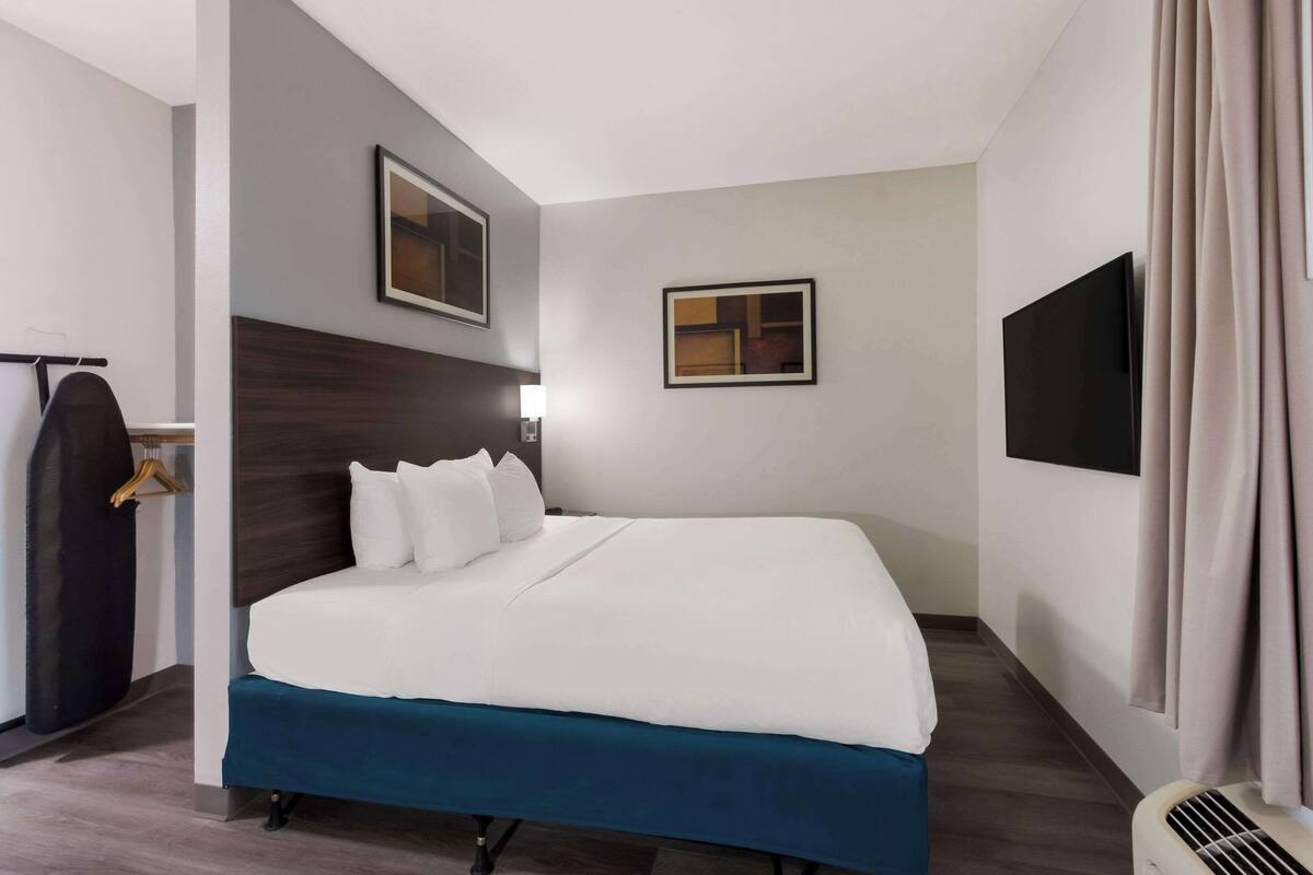 A modern hotel room with a large bed, a flat-screen TV, and a coat rack.