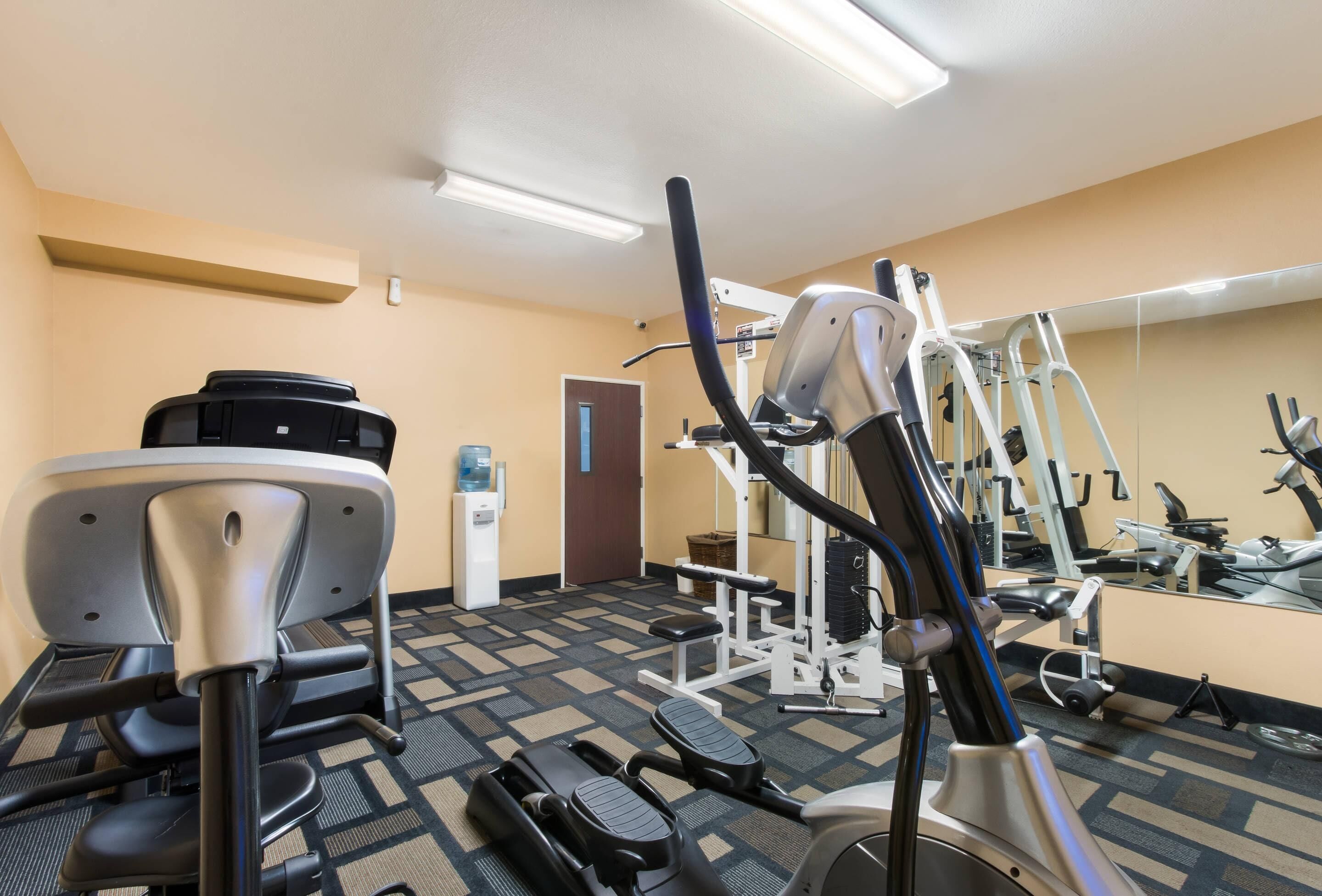A gym with cardio machines, weight equipment, and a water dispenser.