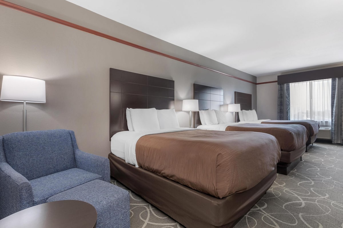A hotel room with a large bed, a smaller sofa, a bedside table, and a lamp.