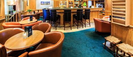 Una zona de bar con muebles de madera, una barra y un área de estar con sillas y mesas.