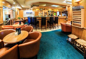Una zona de bar con muebles de madera, una barra y un área de estar con sillas y mesas.