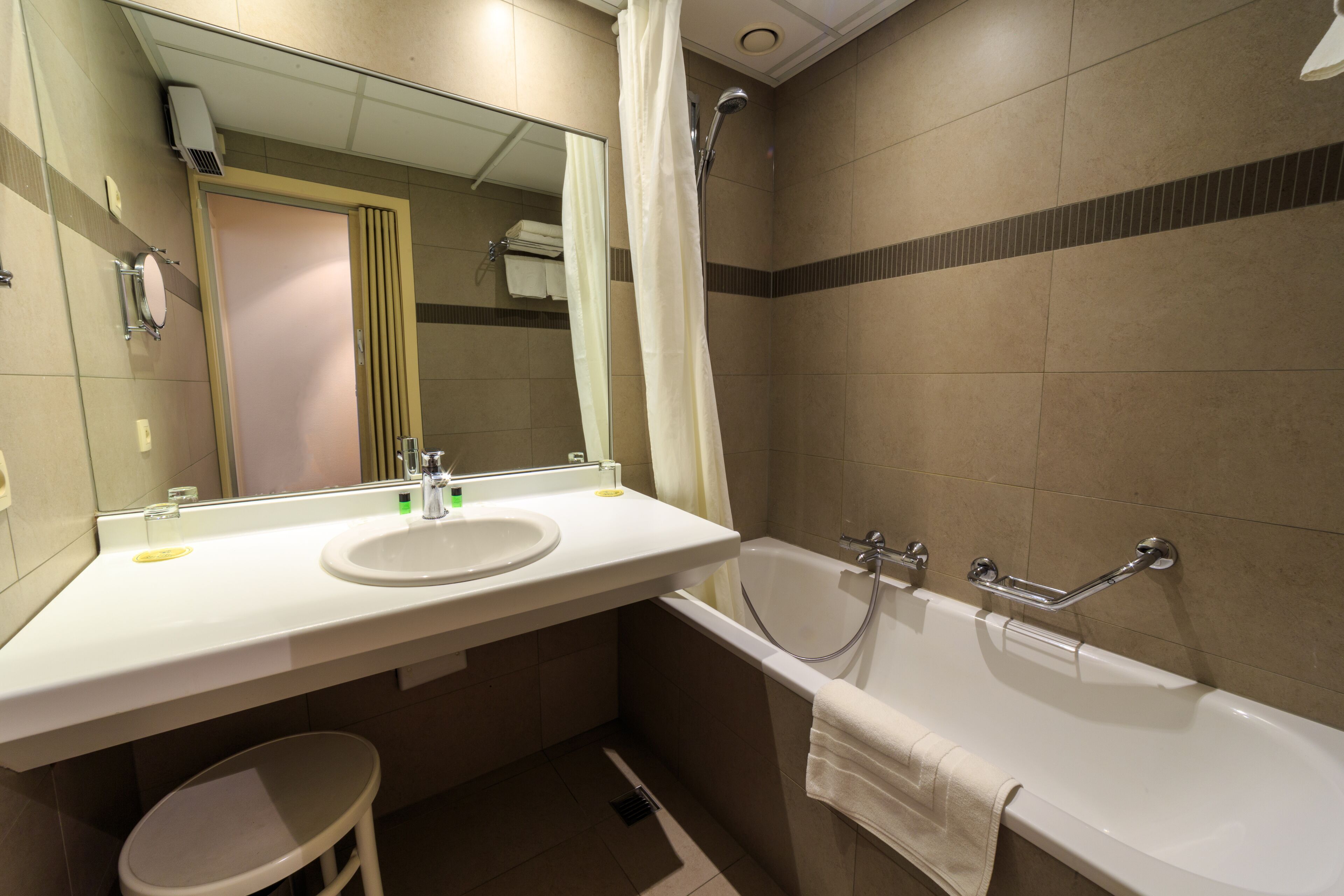 A bathroom with a sink, mirror, shower, and toilet.