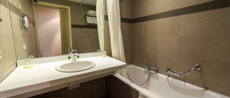 A bathroom with a sink, mirror, shower, and toilet.