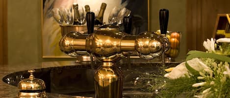 A bar area with a gold-colored faucet, a bottle of champagne, and a bouquet of flowers on the counter.
