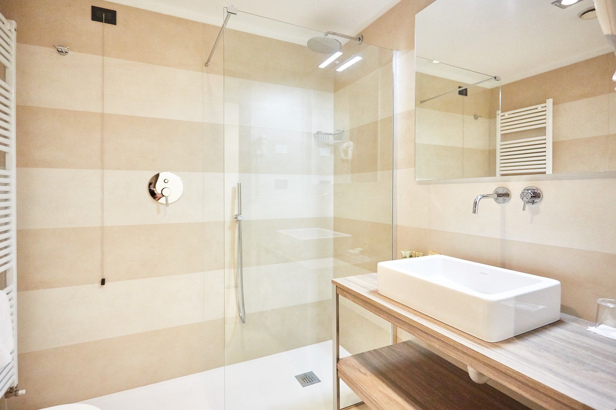 Ein modernes Badezimmer mit einer Duschkabine, einem weißen Waschbecken und einem Holzbadezimmermöbel.