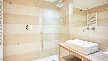 Ein modernes Badezimmer mit einer Duschkabine, einem weißen Waschbecken und einem Holzbadezimmermöbel.