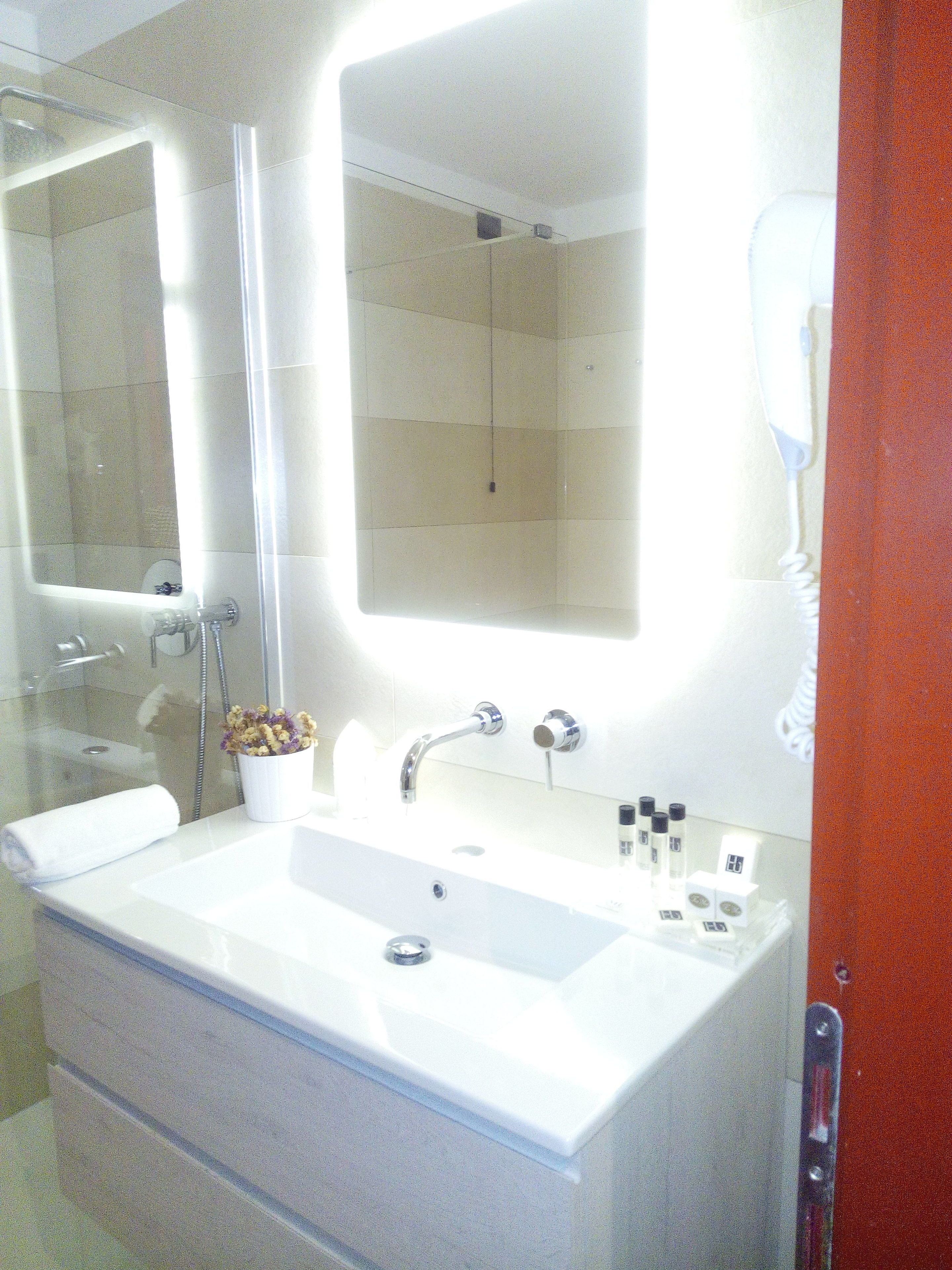 Un baño con un lavabo blanco grande, un espejo y una cabina de ducha de vidrio.